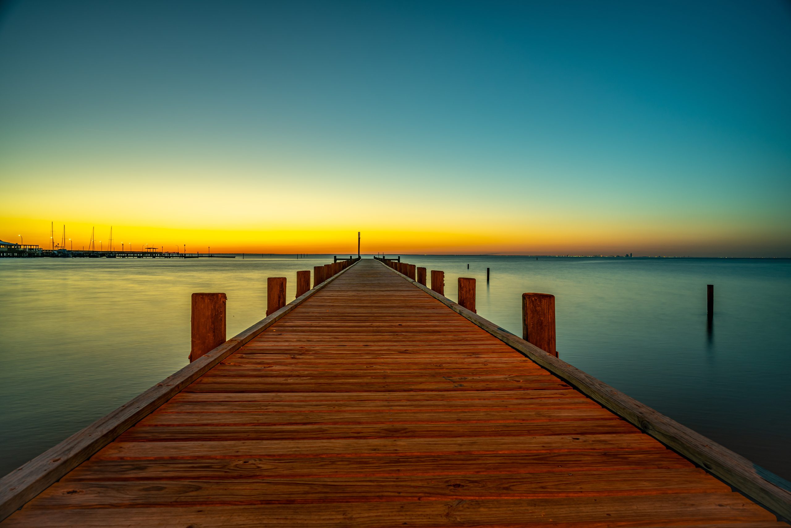 A pier at sunset leading out to a body of water.